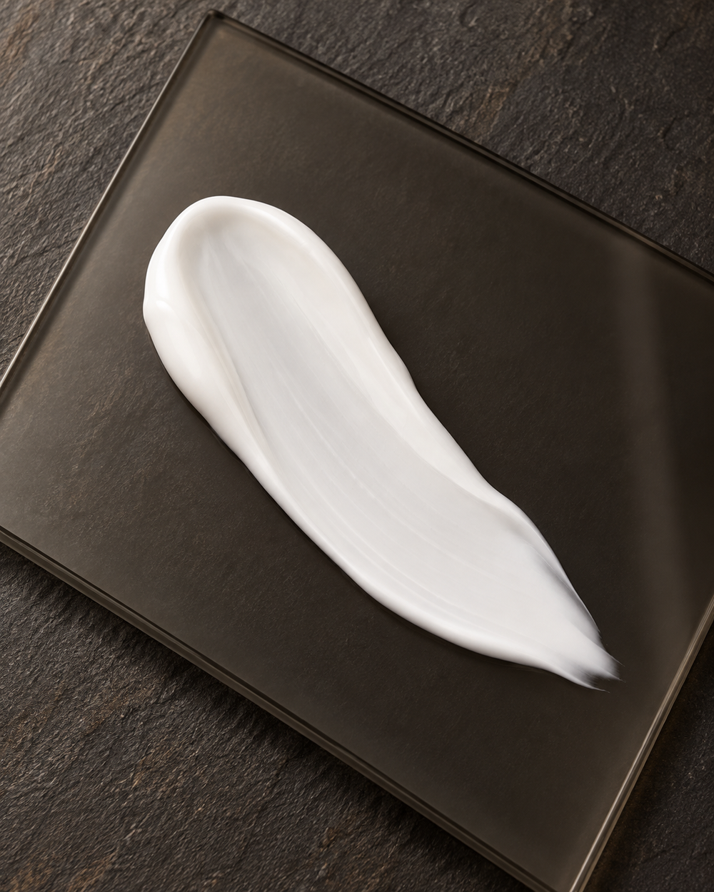 White cream smear on smoky glass.