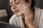 White cleansing lather being massaged across a cheek.
