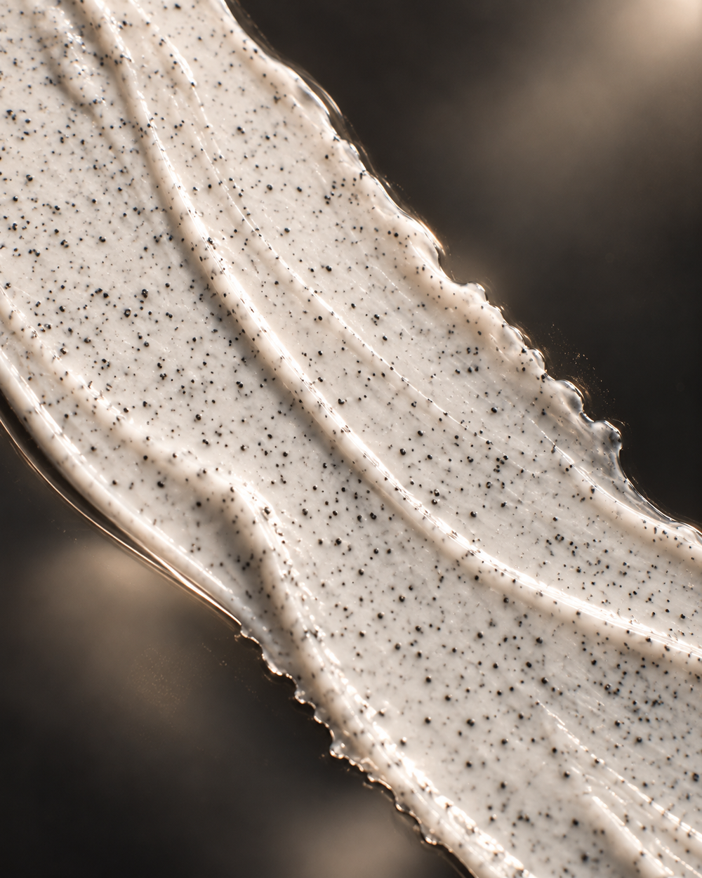 Ivory scrub with fine dark grains across glass.